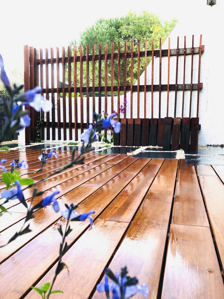 Petit terrasse aménagée : brise-vue en lames bois verticales avec banc intégré sur une terrasse moitié bois moitié dalles ardoise et gravier blanc avec végétaux à Saint-Jean-de-Monts (85)
