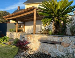 Aménagement d'un petit jardin avec mur en pierres, lame d'eau incrustée, pergola en bois exotique et végétaux aux Sables D'Olonne (85)