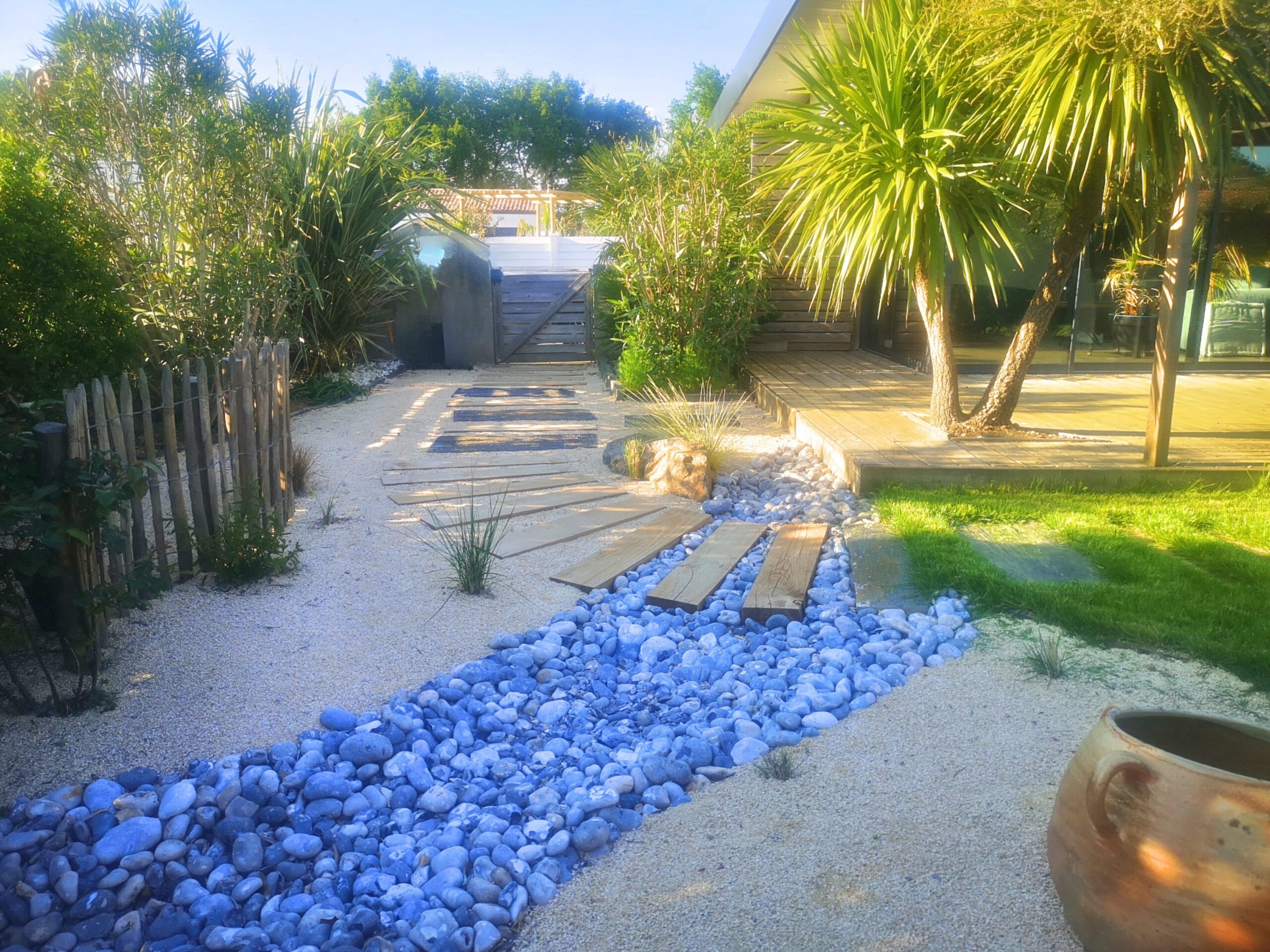 Entrée allée en bastaings de bois et dalles ardoise dans sable de compactage avec rivière de galets Entrée allée en bastaings de bois et dalles ardoise dans sable de compactage avec rivière de galets