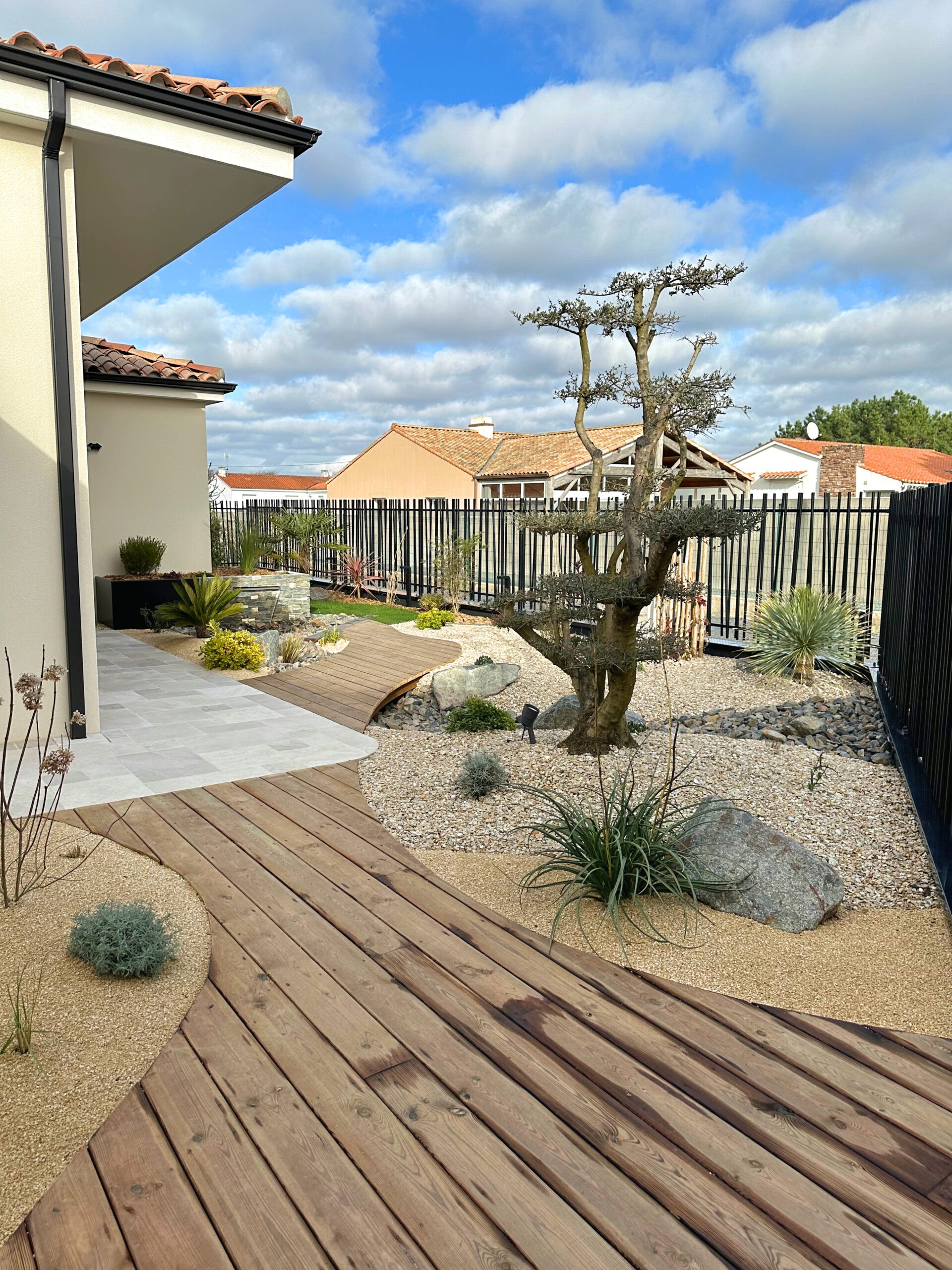 Terrasse et passerelle en pin entre les massifs en sable et gravier Terrasse et passerelle en pin entre les massifs en sable et gravier