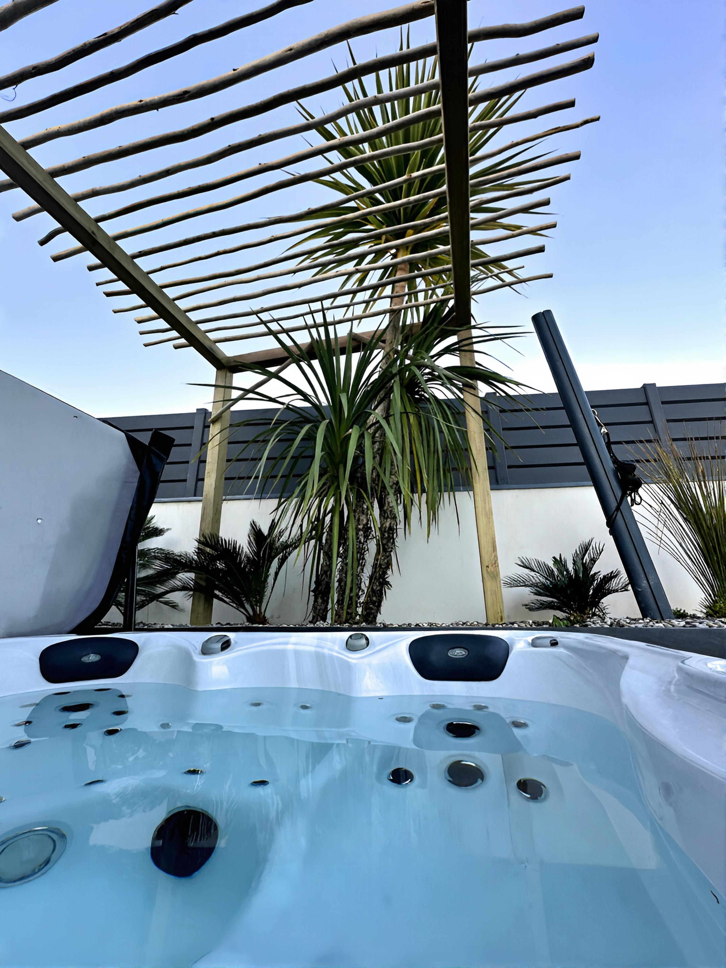 Une pergola en perches d'eucalyptus filtre la lumière au-dessus du spa